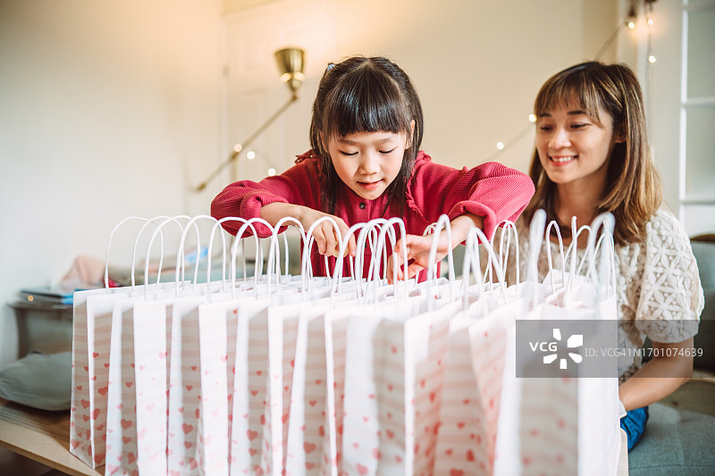 快乐的女孩和妈妈在家准备生日派对的礼品袋图片素材