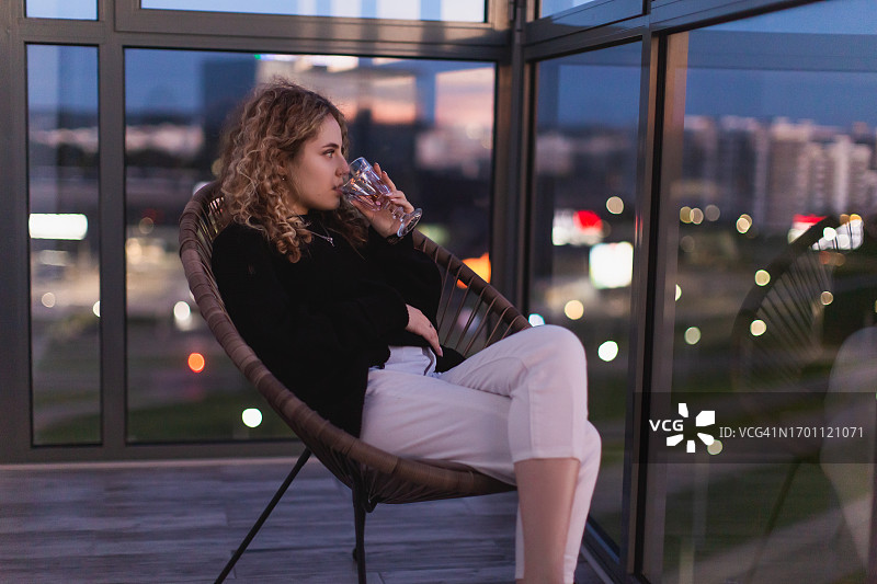 在阳台上放松的卷发红发女人图片素材