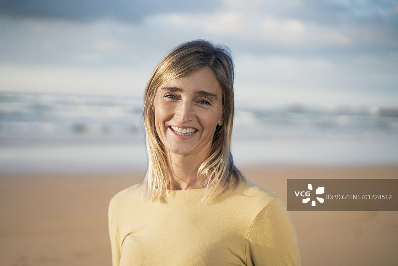 在海滩上微笑的金发女人图片素材