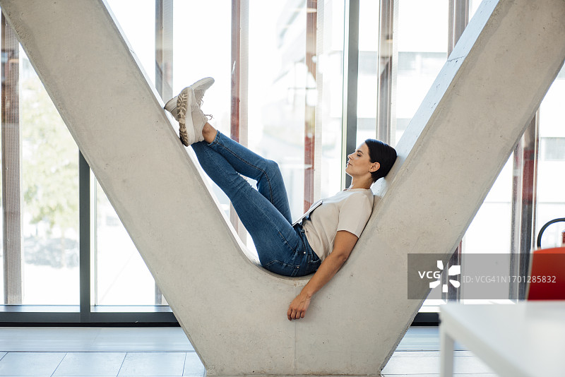 在办公室走廊V形柱子上休息的女商人图片素材