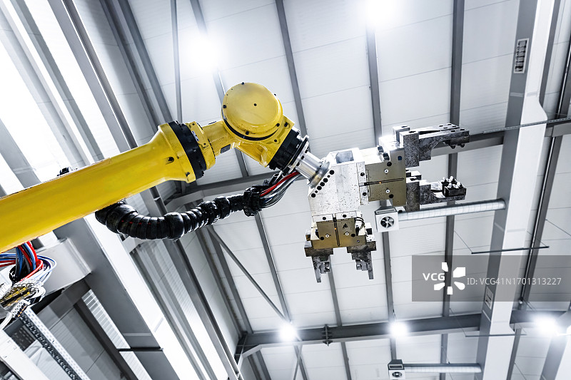 工厂天花板下带有机器的黄色机械臂图片素材