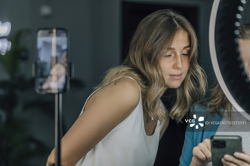 理发师在美发沙龙向顾客展示智能手机图片素材