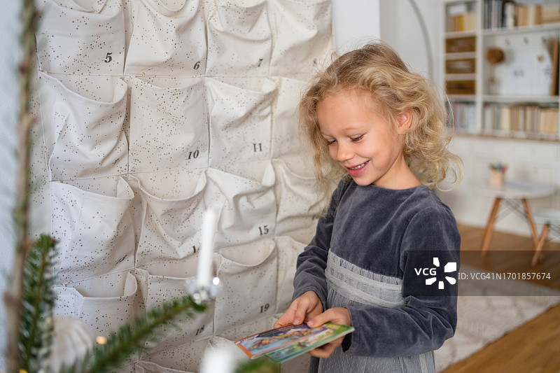 在客厅打开圣诞节日历的惊讶女孩图片素材