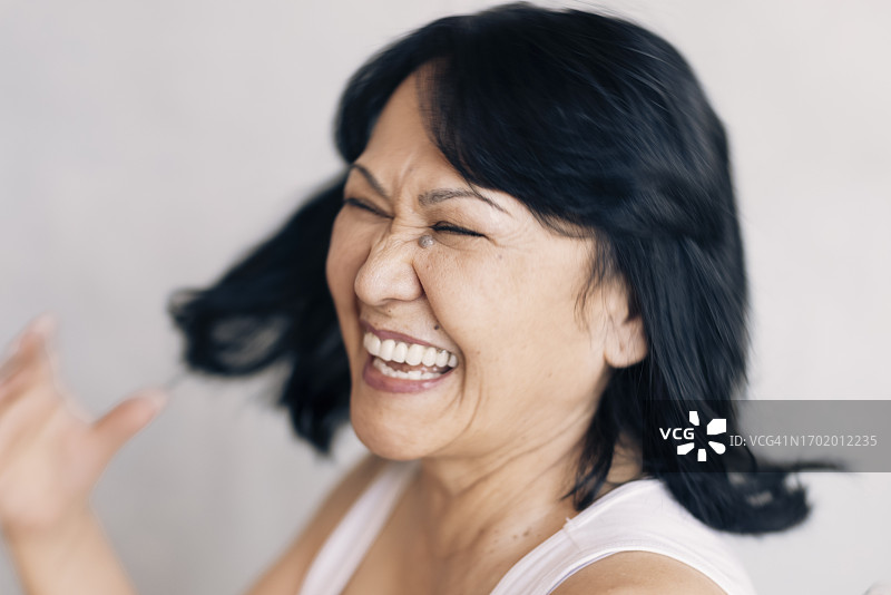 快乐的中年妇女闭着眼睛笑着，背景是白色图片素材