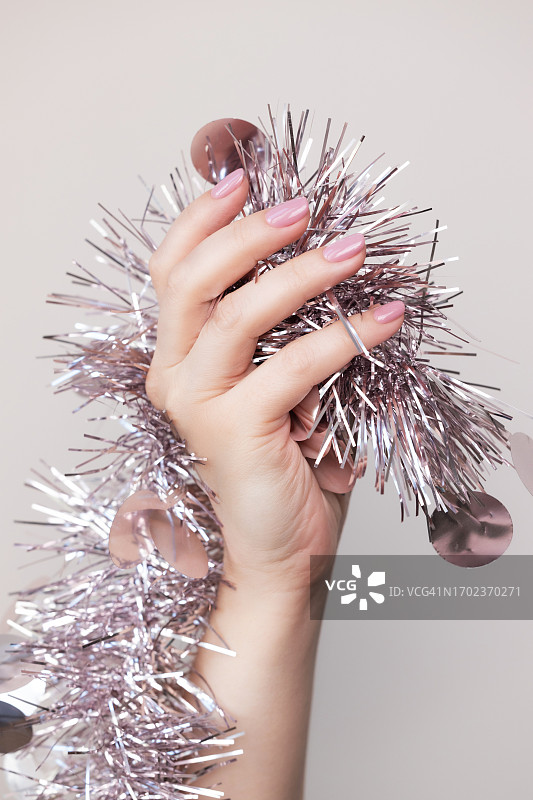 手部美甲特写：粉色凝胶美甲与圣诞装饰图片素材