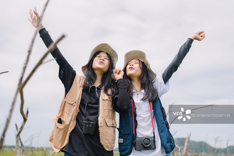 一对少女双胞胎姐妹在森林的草地上和清晨的天空下散步图片素材