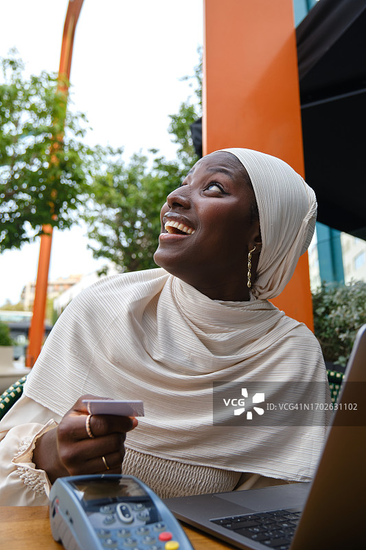 在自助餐厅用信用卡支付的分心穆斯林女性图片素材