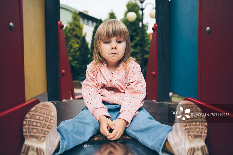 坐在滑梯上的悲伤女孩图片素材