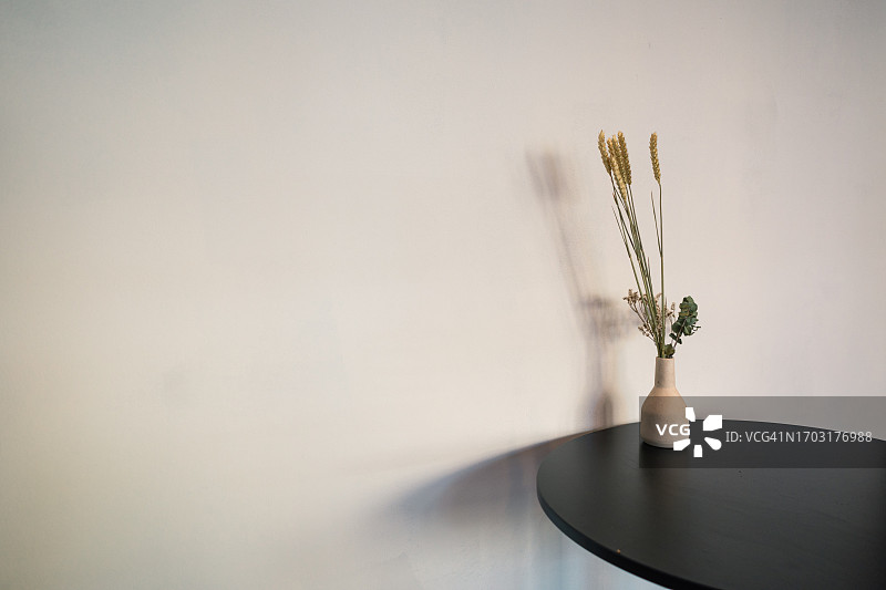 陶瓷花瓶中的干花，在圆形黑色咖啡桌上图片素材
