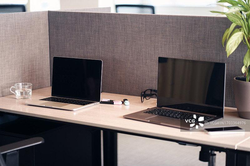 两台笔记本电脑和桌面上的数位板，双人办公室工作场所，带复制空间的背景图片素材