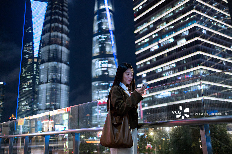 商务女士站在中国上海金融区使用智能手机图片素材