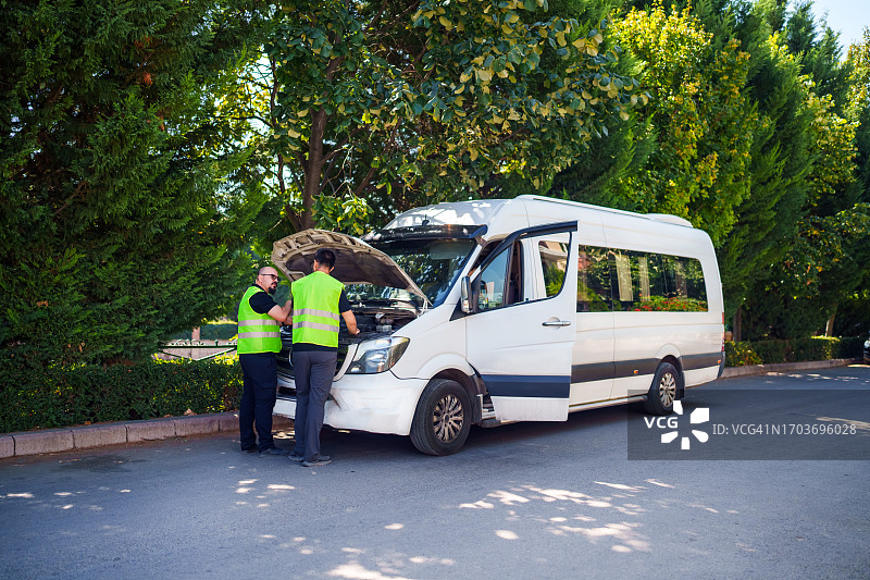 两名男子打开白色厢型车的前引擎盖图片素材