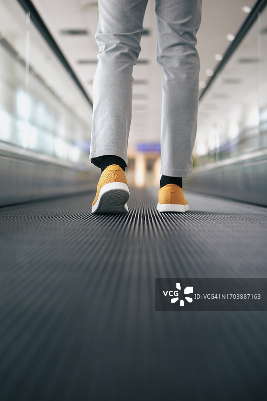 穿着考究的男人站在自动人行道上，露出腿图片素材