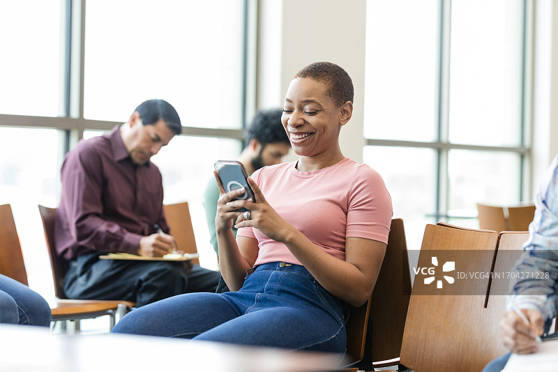 年轻女子在看社交媒体时微笑图片素材