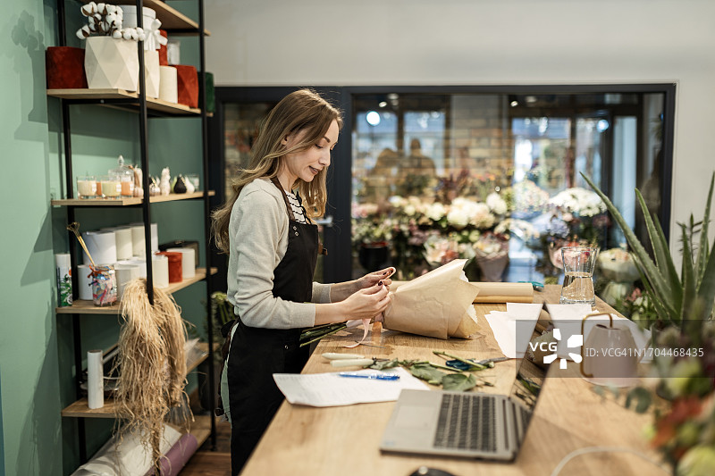 面带微笑、展示插花技术的花艺师图片素材