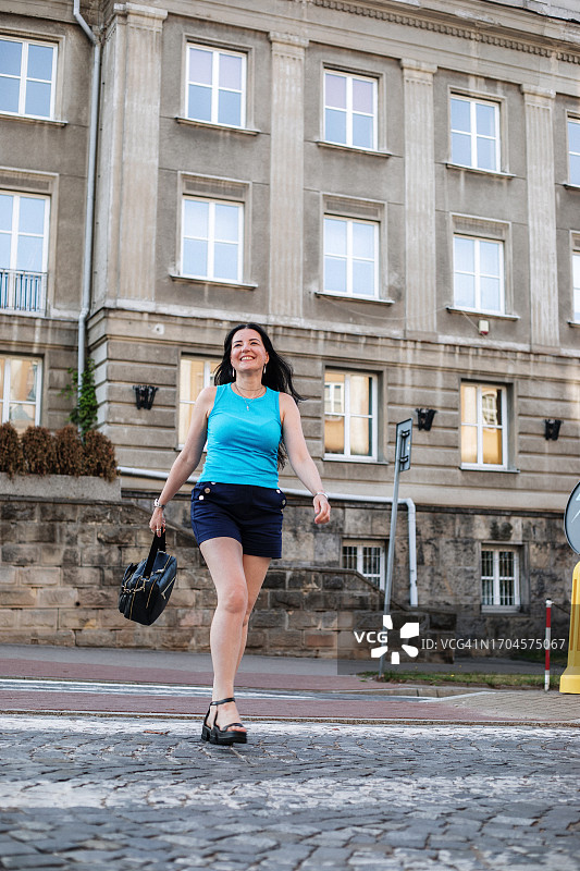 穿着休闲服装的探险女游客自信地走在繁华的市中心街道上图片素材