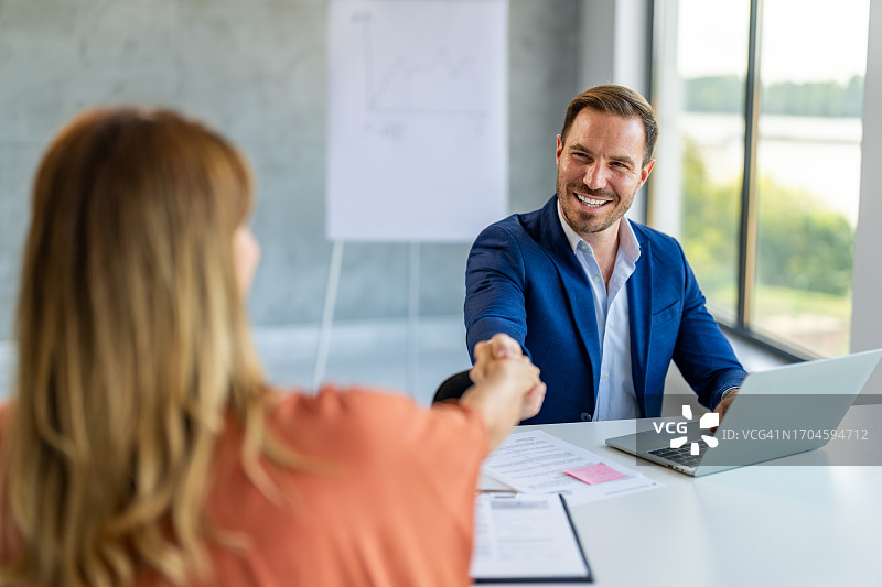 快乐英俊的经理与新女员工握手图片素材