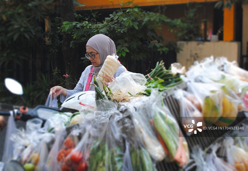 戴头巾的妇女早上在流动蔬菜店购买蔬菜和食物图片素材