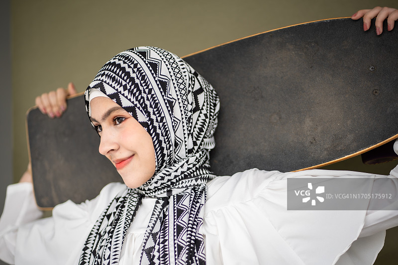 戴着头巾的年轻女子拿着滑板图片素材