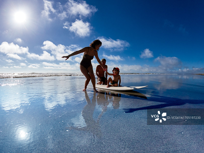 情侣教孩子在海里冲浪图片素材