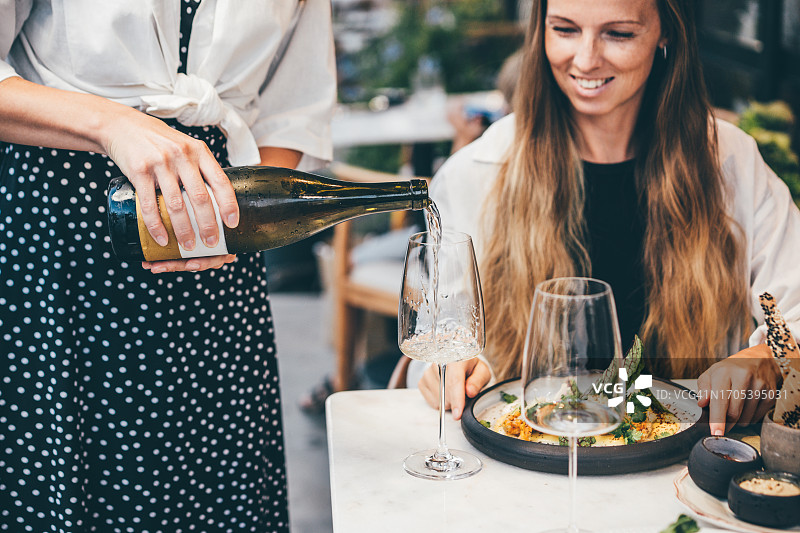 服务员在户外餐厅为顾客倒酒图片素材