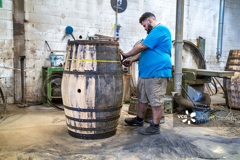 雪利酒桶厂工人测量桶的直径，以确保它们完全相同图片素材