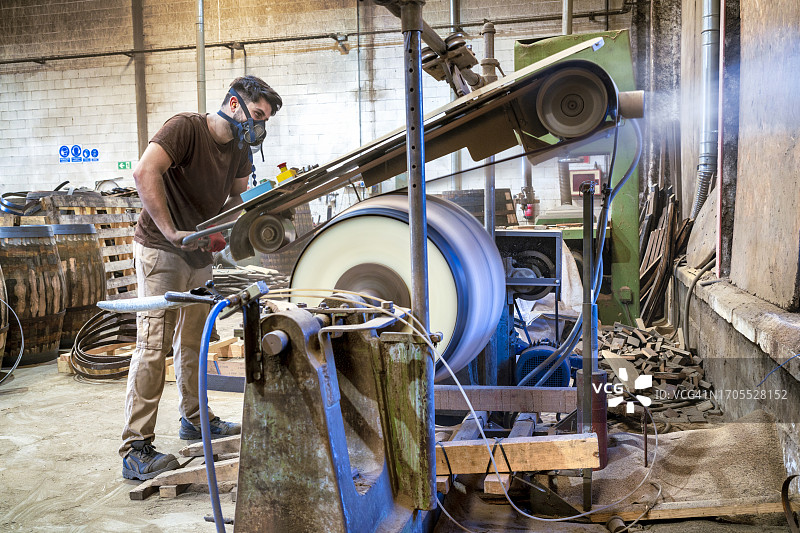 工人在雪利酒桶厂用机器抛光美国橡木桶板图片素材