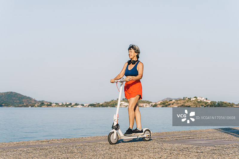 夏日海边，老年妇女骑电动滑板车旅行图片素材