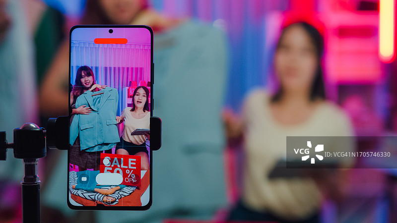 年轻亚裔女性直播展示新款时装图片素材