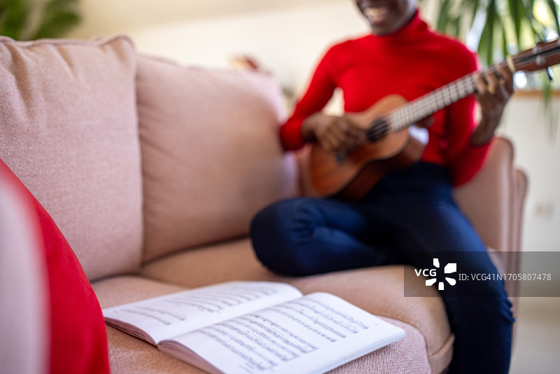 年轻女人在家看乐谱弹尤克里里图片素材