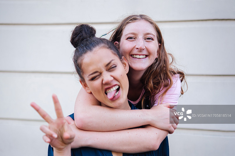 两个年轻的朋友拥抱并对着镜头做鬼脸图片素材