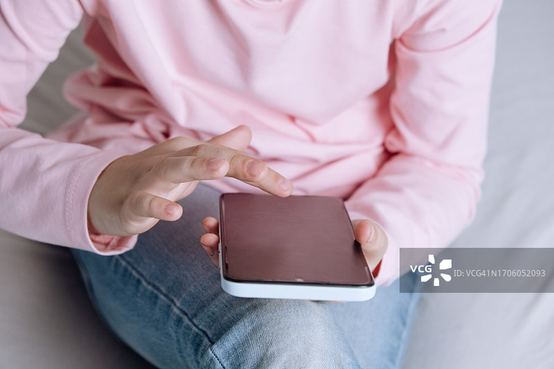 孩子在床上用手机刷社交媒体图片素材