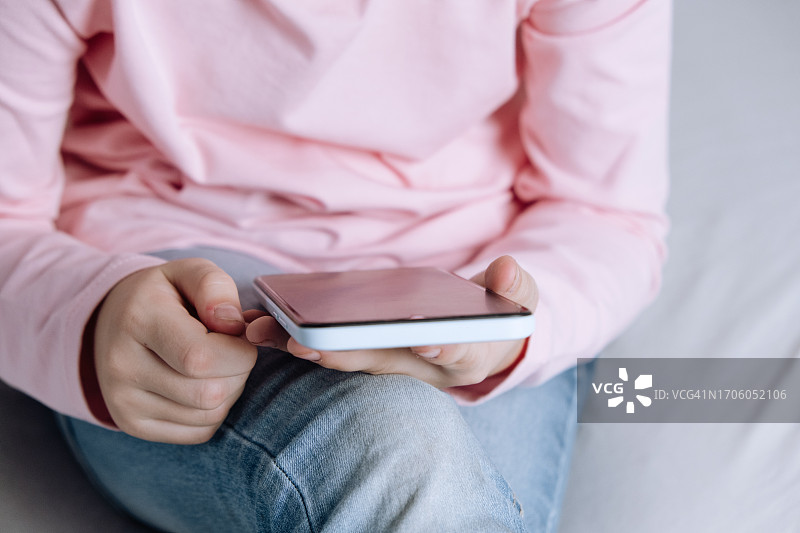 孩子在床上用手机刷社交媒体图片素材