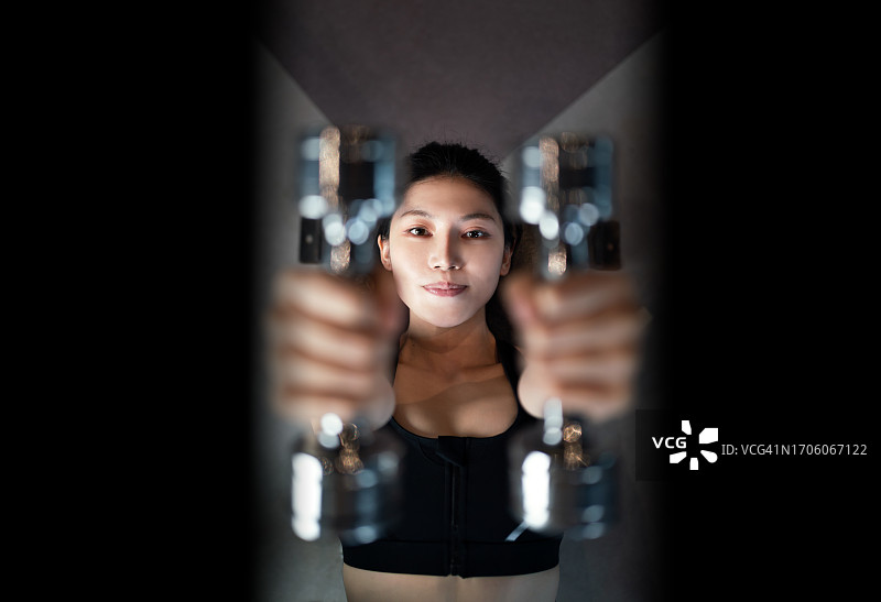 年轻女子在健身房进行举重训练图片素材