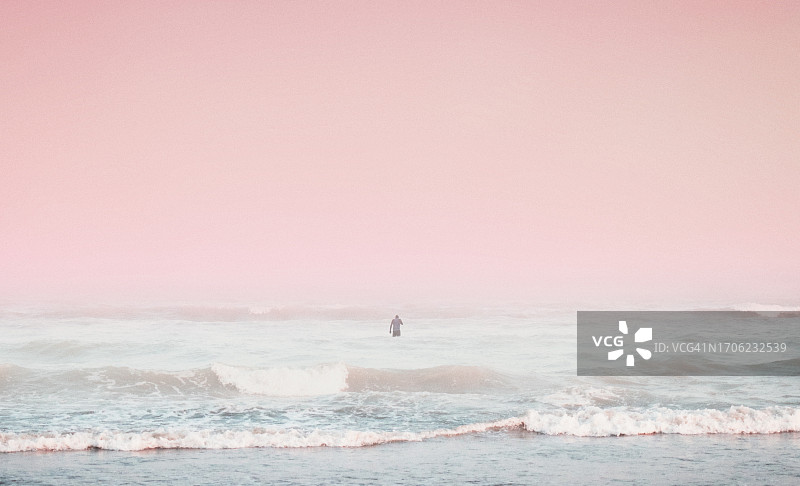 伊朗霍尔木兹甘省阿巴斯港粉色日落时分海中游泳者的风光图片素材