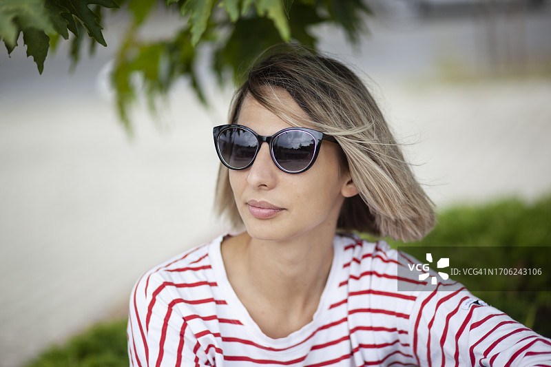 坐在公园里的戴太阳镜的金发女子肖像图片素材