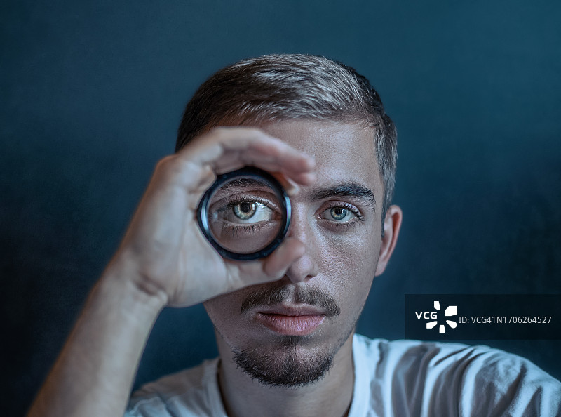 手持眼镜单眼观看的男人肖像，心理健康问题概念图片素材