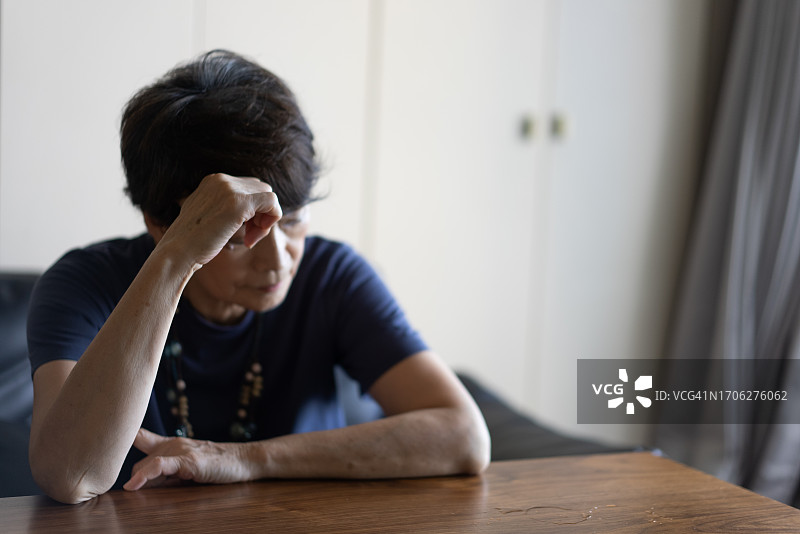 一位老妇人坐在沙发上，感到很苦恼图片素材