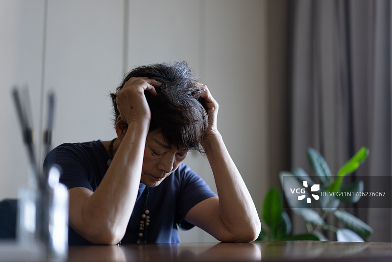 一位老妇人坐在沙发上，感到很苦恼图片素材