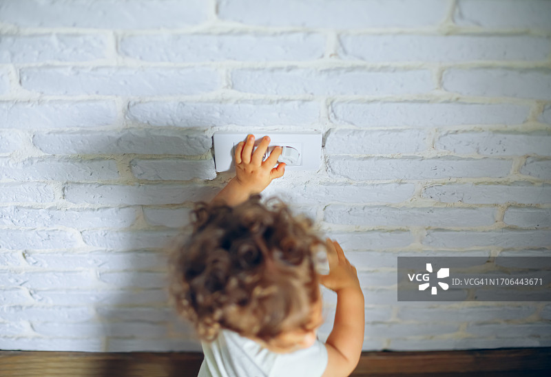 宝宝触摸墙上的电源插座图片素材