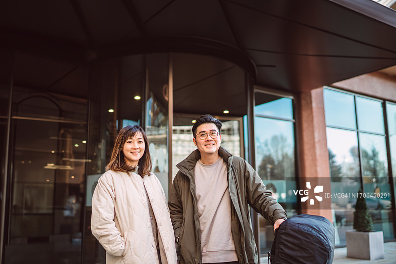 年轻情侣带行李在酒店前等出租车图片素材