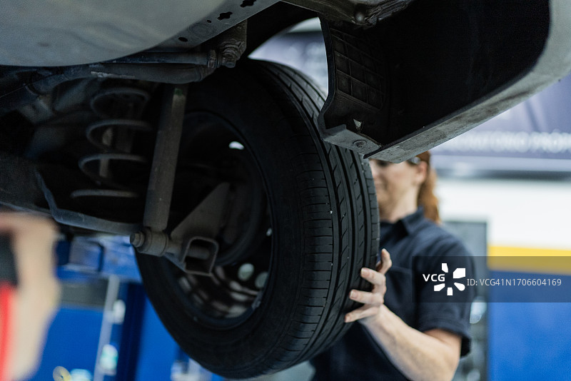 汽车修理女工在修理店更换汽车车轮图片素材