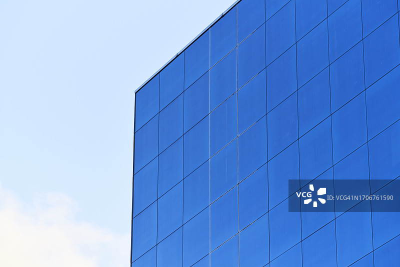 蓝色玻璃建筑外墙的仰视角度照片，天空为背景图片素材