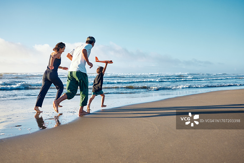 父母和拿着飞机模型的儿子奔跑图片素材