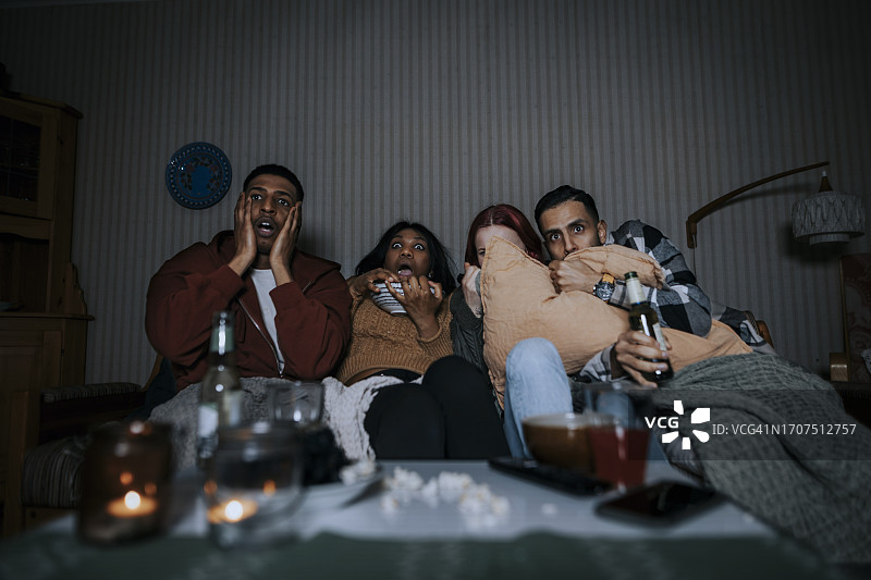 在小木屋里看恐怖电影的害怕的多民族朋友图片素材