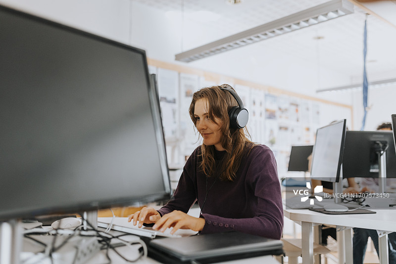 年轻女人在学校实验室戴耳机用电脑图片素材
