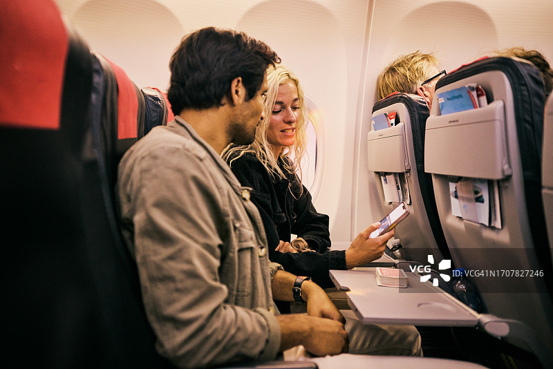 年轻夫妇坐在飞机上享受周末旅行图片素材