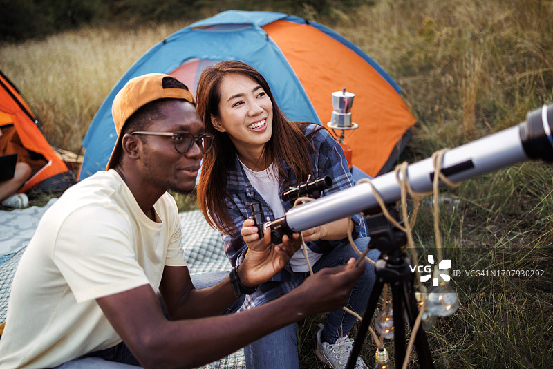 年轻休闲夫妇在森林露营时架设望远镜图片素材