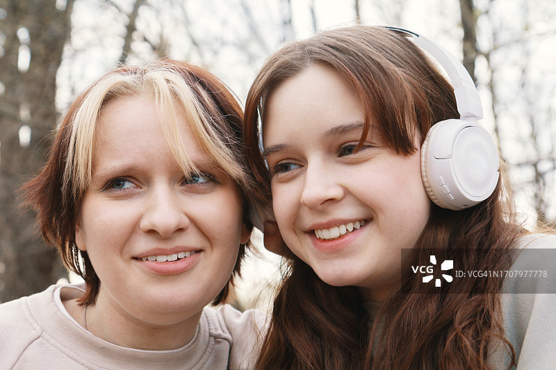 两个十几岁的女性朋友在户外无线耳机上听音乐的肖像图片素材