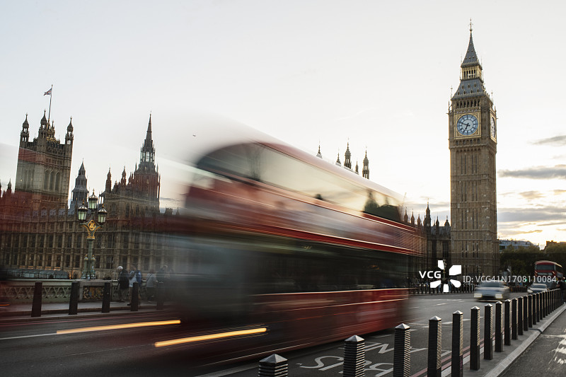 伦敦威斯敏斯特桥上的红色双层巴士虚焦照片，远处可见大本钟和威斯敏斯特宫图片素材